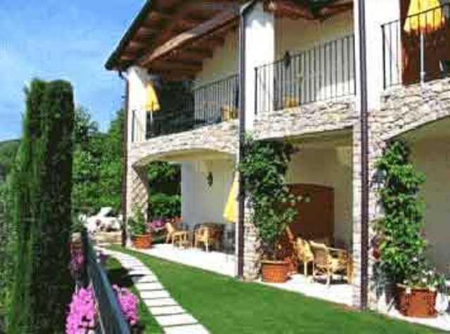 una casa con patio e un cortile con prato verde di Villa Giada a Torri del Benaco