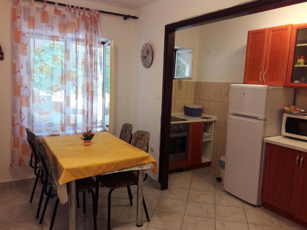 eine kleine Küche mit einem Tisch und einem Kühlschrank in der Unterkunft Apartmani Dokoza in Drage