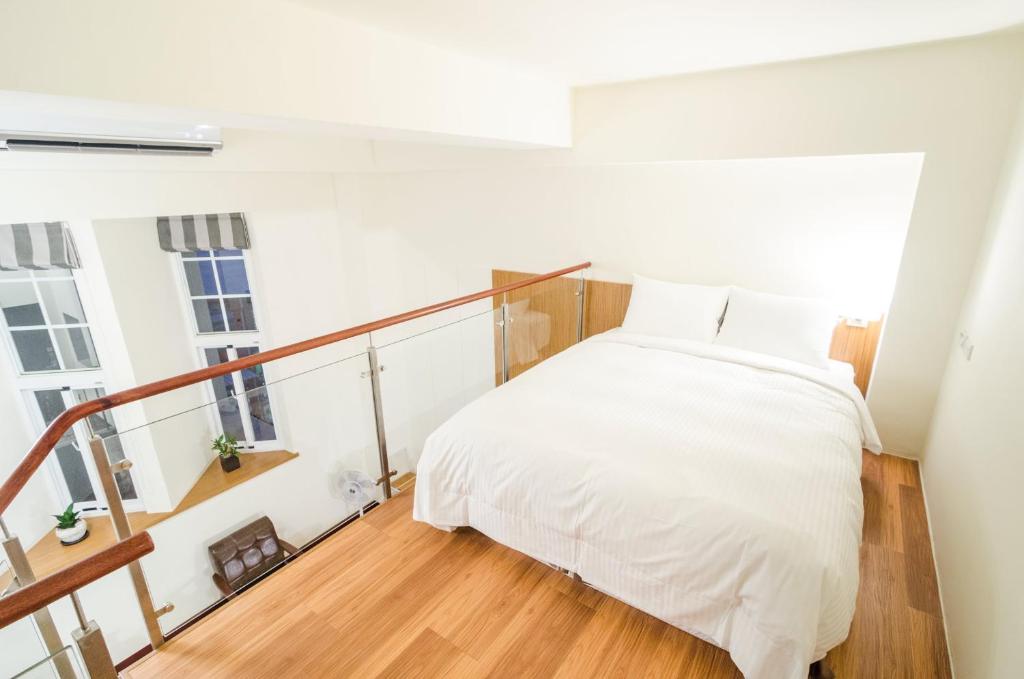 a bedroom with a white bed and a staircase at Anping Kensington Hotel in Anping