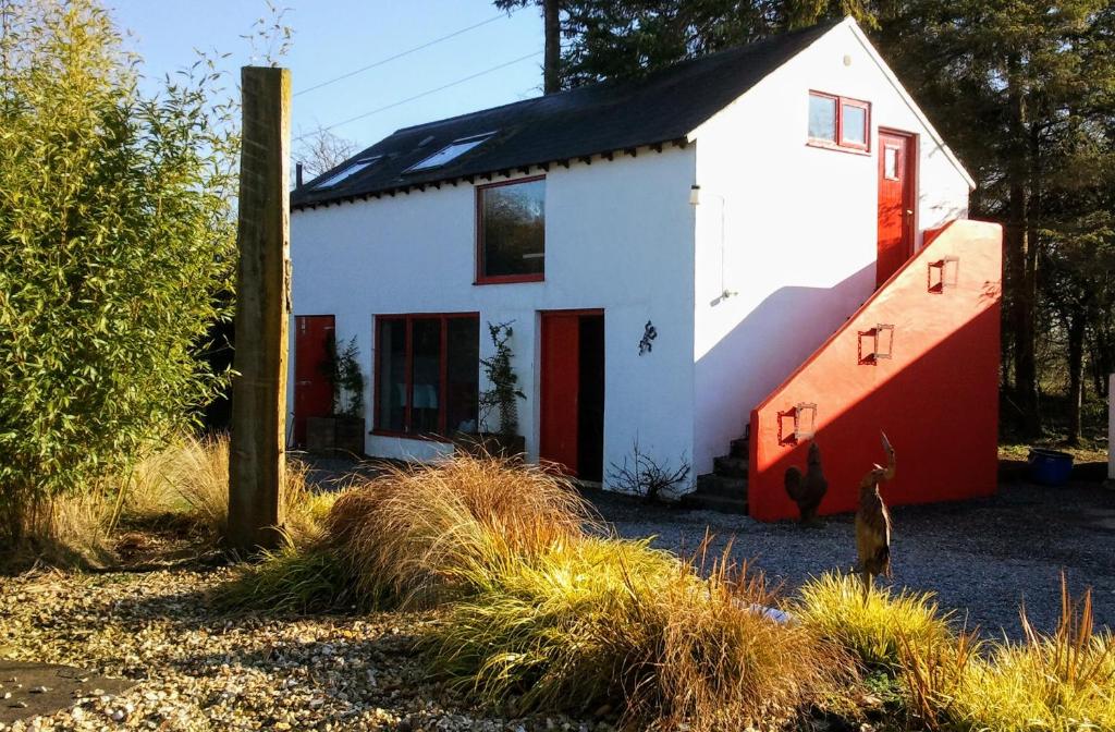 una casa blanca y roja con techo negro en The Village Studio Apartments, en Moate