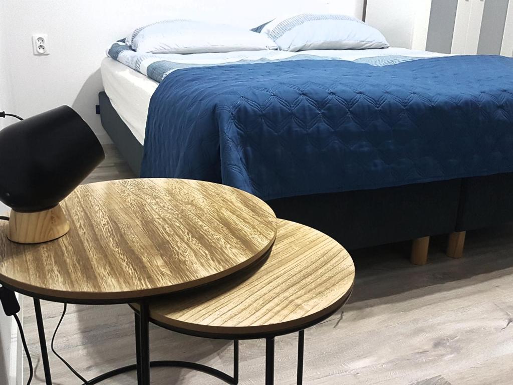カルビアにあるPrzy Plażyのベッドルーム1室(テーブル2台、青いシーツ付きのベッド1台付)