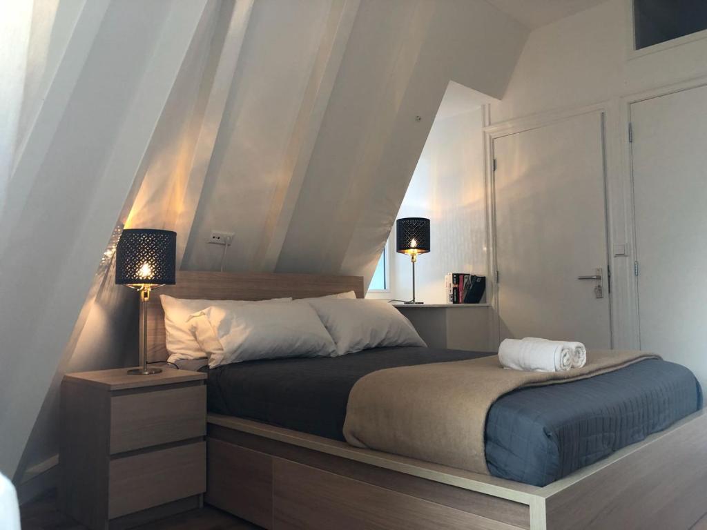 ein Schlafzimmer mit einem Bett, einem Nachttisch und einer Lampe in der Unterkunft A'DAM CENTRE CHIC in Amsterdam