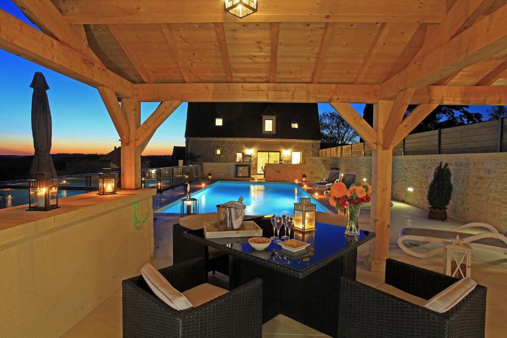 een terras met een tafel en stoelen naast een zwembad bij La Malonie in Sarlat-la-Canéda