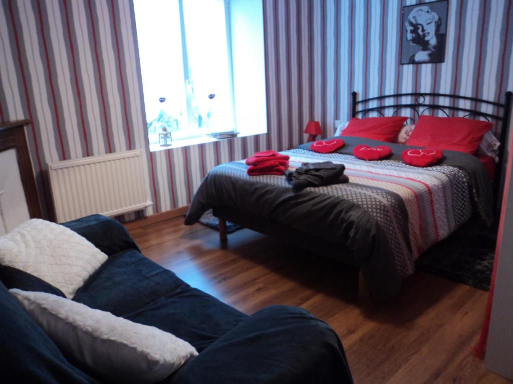 a bedroom with a bed with red pillows and a couch at TY LOUISETTE in Bannalec