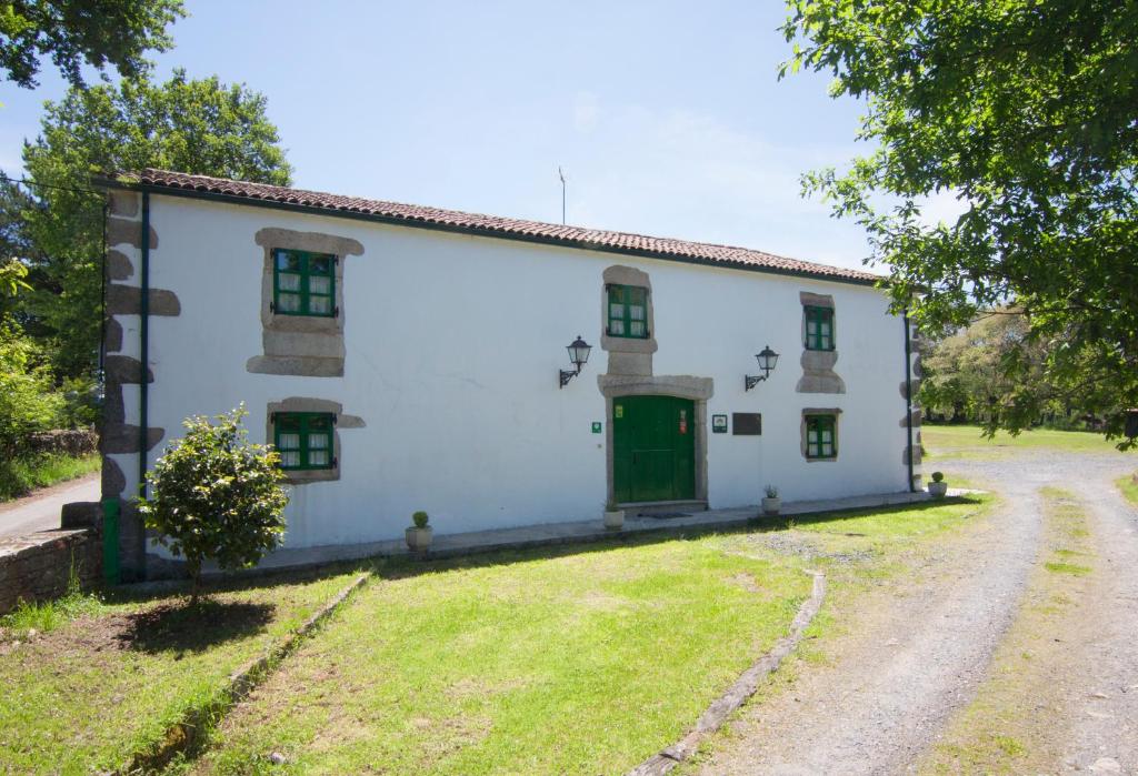 a white house with a green door on a road at Casa Blanco in Palas de Rei