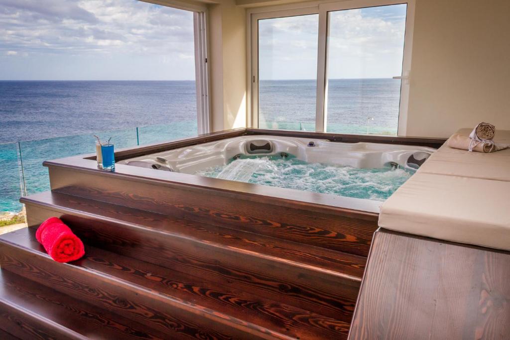 a bath tub with a view of the ocean at Lux Apartments in Xgħajra