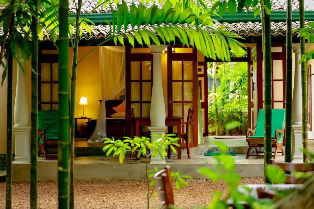 une maison avec une terrasse couverte dotée d'une table et de chaises dans l'établissement Lenora Villas, à Bentota