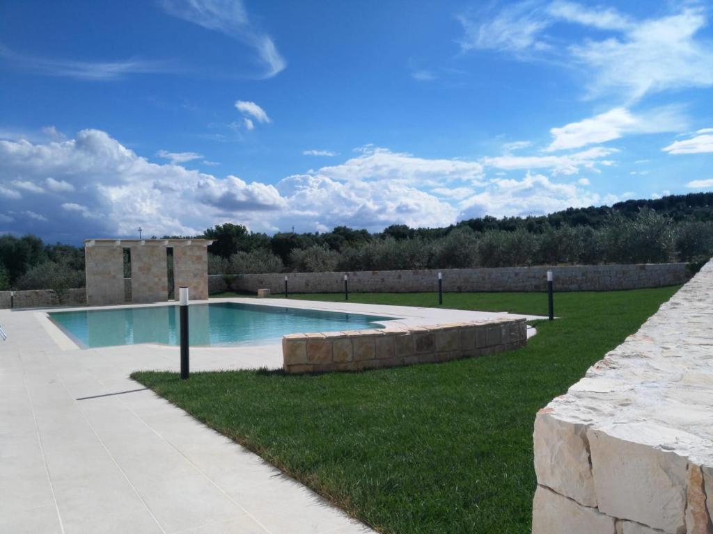 a swimming pool in a yard with a stone wall at I Trulli di Gina Appartamento 4 persone in Monopoli