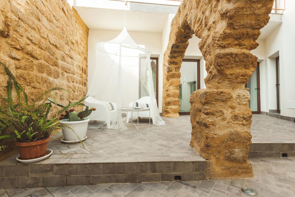 una camera con un muro in pietra e un tavolo con sedie di Cortile Baronello a Agrigento