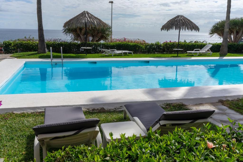een zwembad met stoelen en de oceaan op de achtergrond bij Apartment Sea View Playa del Ingles in Playa del Inglés