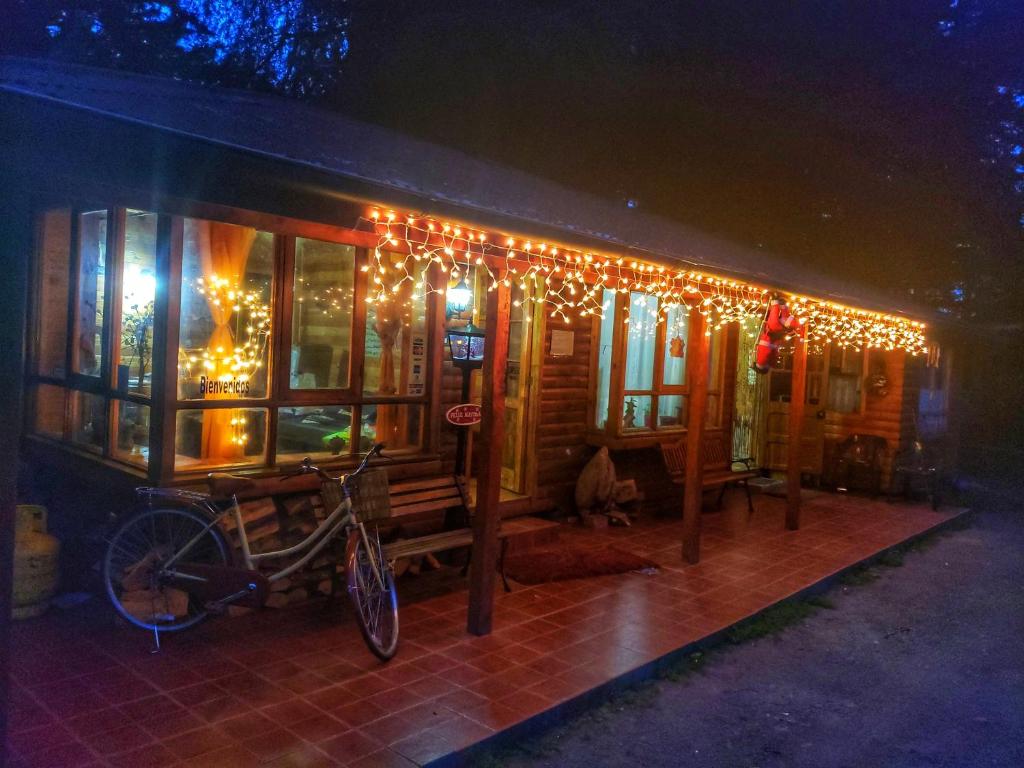 Una casa con luces de Navidad en un lado. en Mae Joa Turismo - Cabañas & Camping Familiar en Ancud