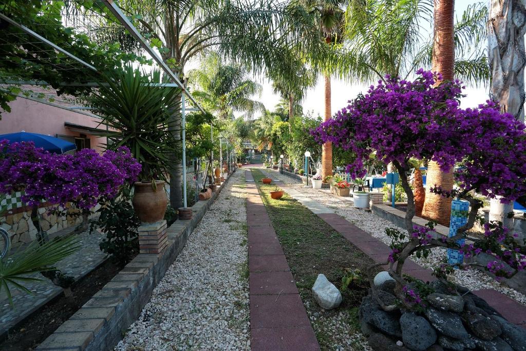 una calle con flores púrpuras y palmeras en Holiday Maison Villa Arci en Giardini Naxos