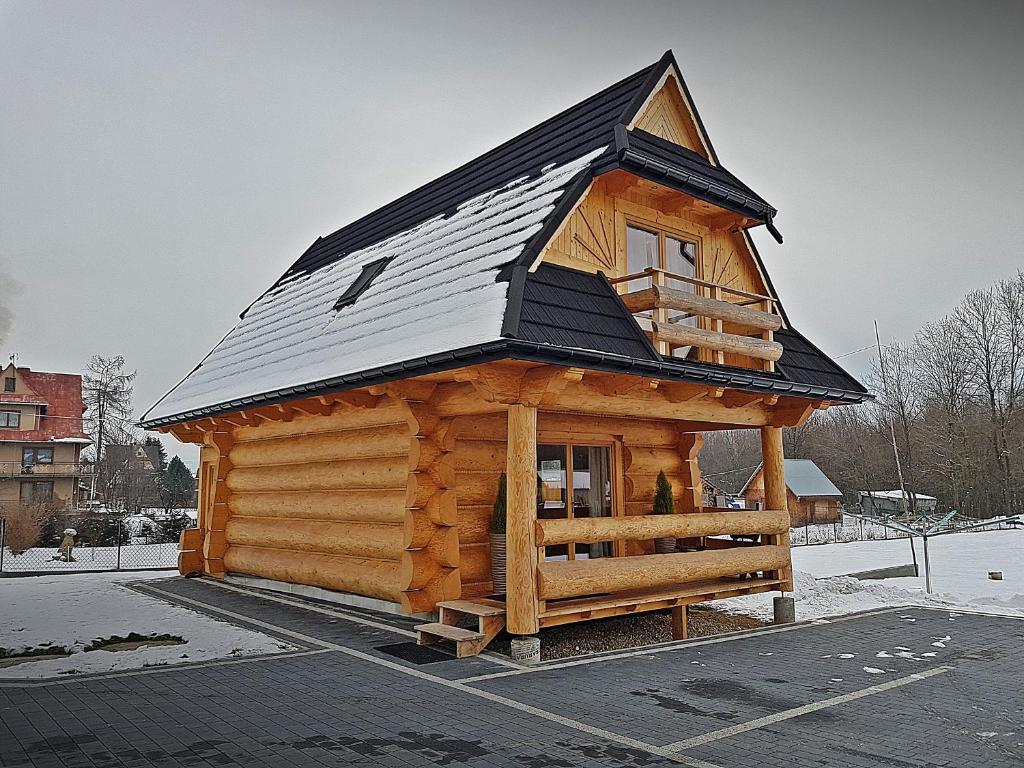 a log cabin with a roof on a parking lot at Domki u Czerników in Białka Tatrzanska