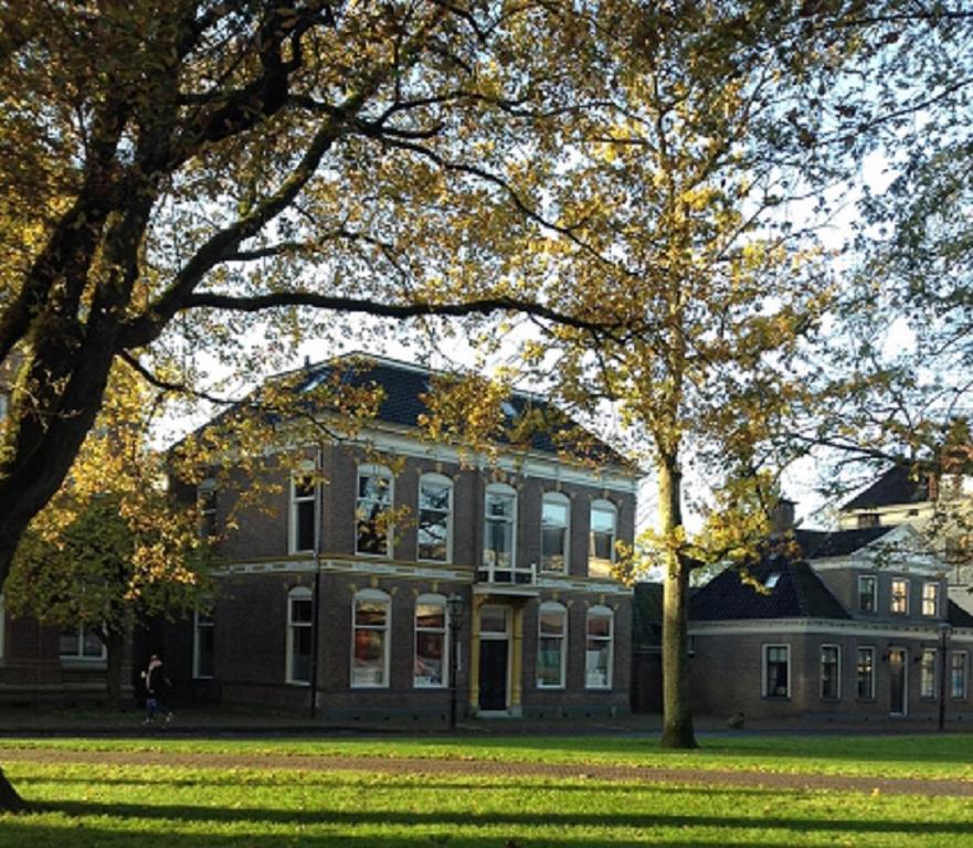 un grand bâtiment en briques avec des arbres devant lui dans l'établissement "In de Kloosterhof" Gratis privé parkeren, à Assen