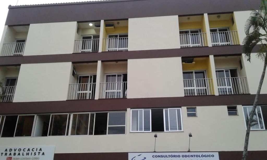 Apartment-Gebäude mit Balkon und Palme in der Unterkunft Castanheiras 3 Quartos in Guarapari