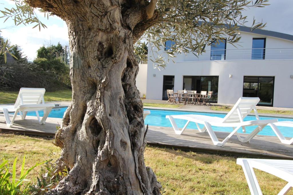 a table and chairs next to a tree next to a pool at Contemporary Villa of Kerseal in Gouesnach
