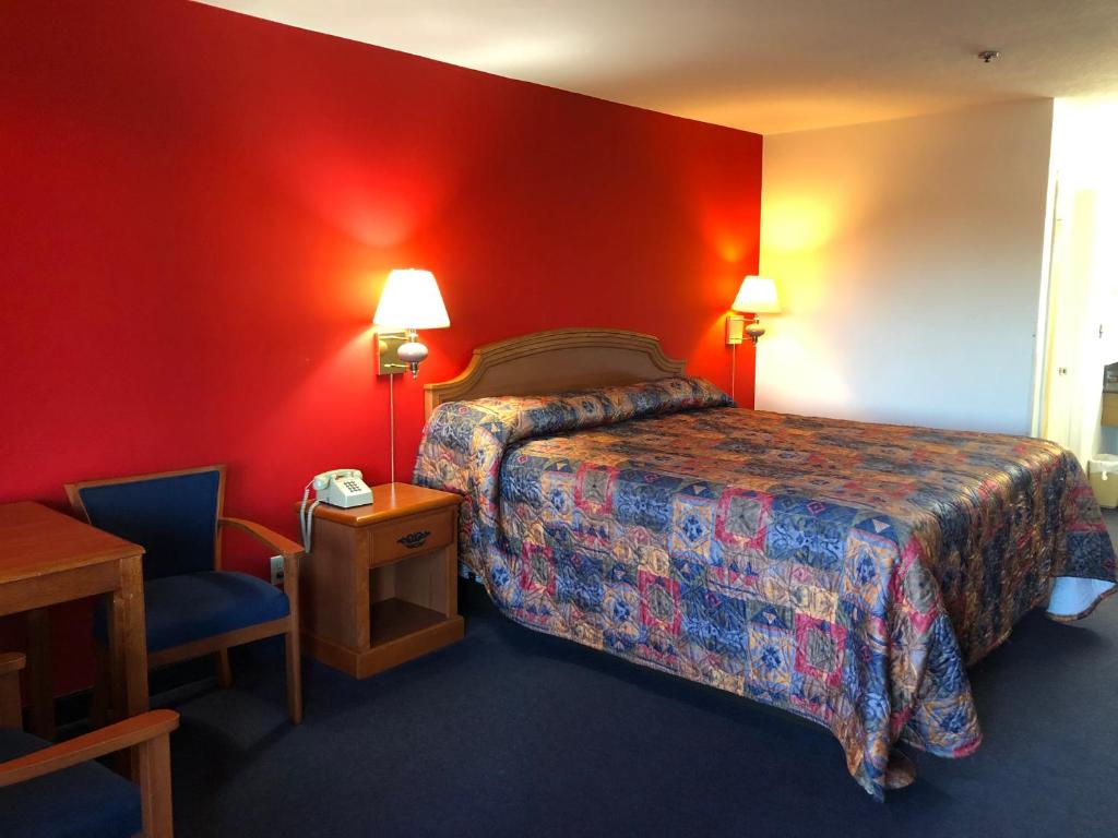 Habitación de hotel con cama y silla en Luxury Inn, en Norwalk