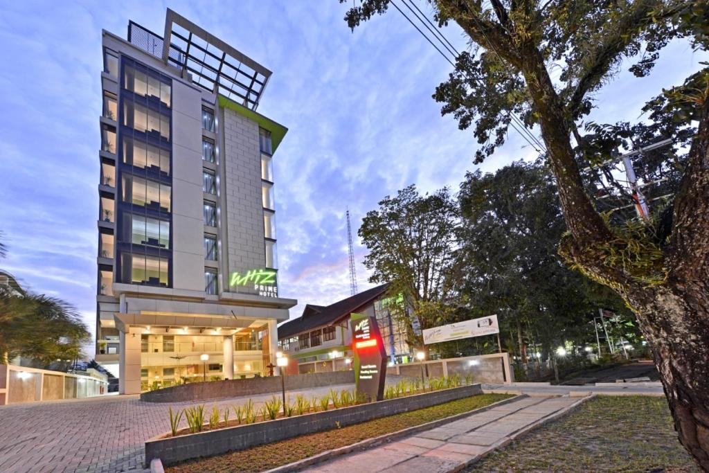 a hotel building with a tree in front of it at Whiz Prime Hotel Khatib Sulaiman Padang in Padang