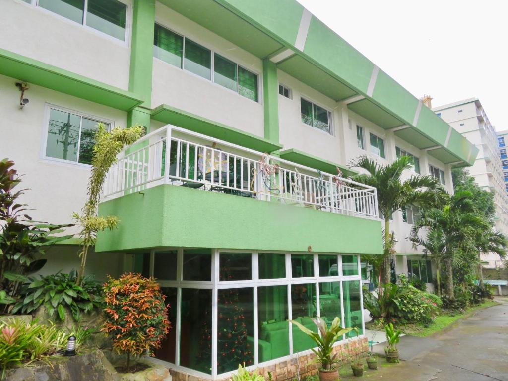un edificio verde y blanco con personas sentadas en un balcón en All Care Bed and Breakfast, en Tagaytay
