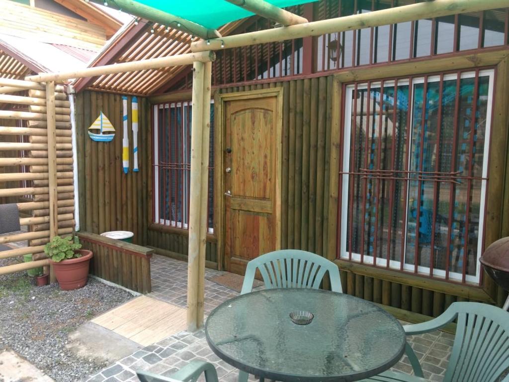 - un patio avec une table et des chaises et un bâtiment en bois dans l'établissement Las 3 Golondrinas, à El Quisco
