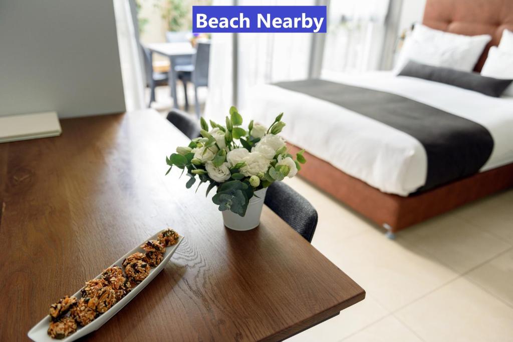 einen Tisch mit einer Vase Blumen und einem Teller Essen in der Unterkunft Sea Land Suites in Tel Aviv