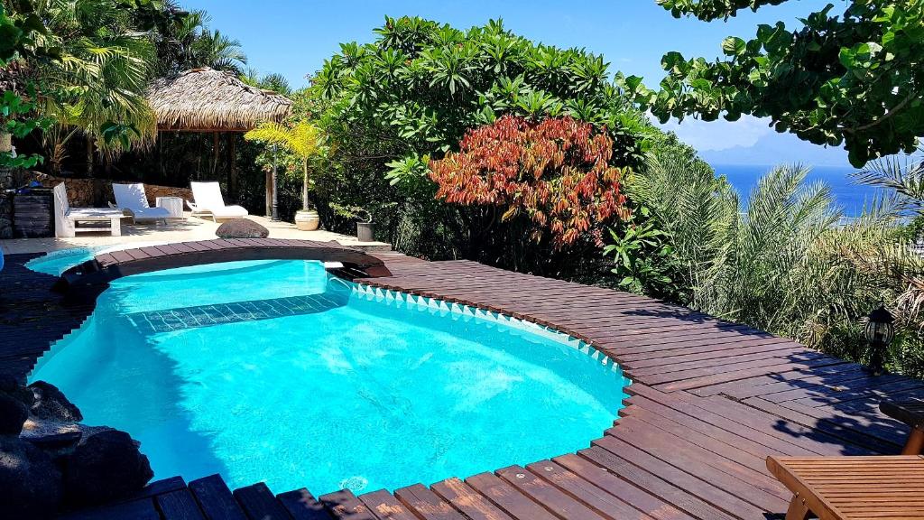 a swimming pool sitting next to a wooden deck at Chalet De Tahiti in Punaauia