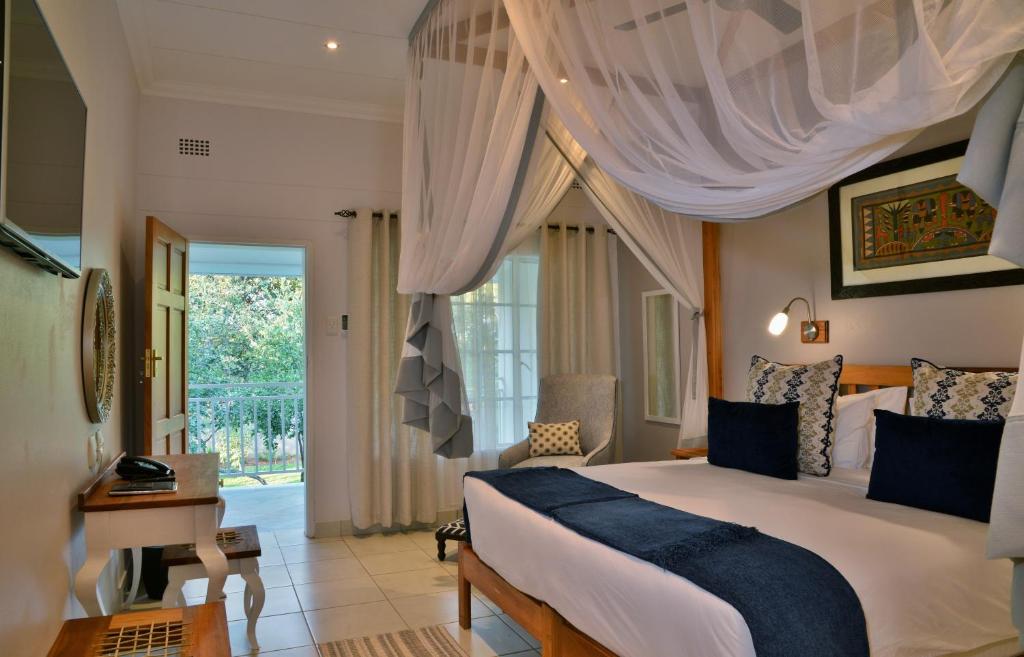 a bedroom with a bed and a desk and a window at Batonka Guest Lodge in Victoria Falls