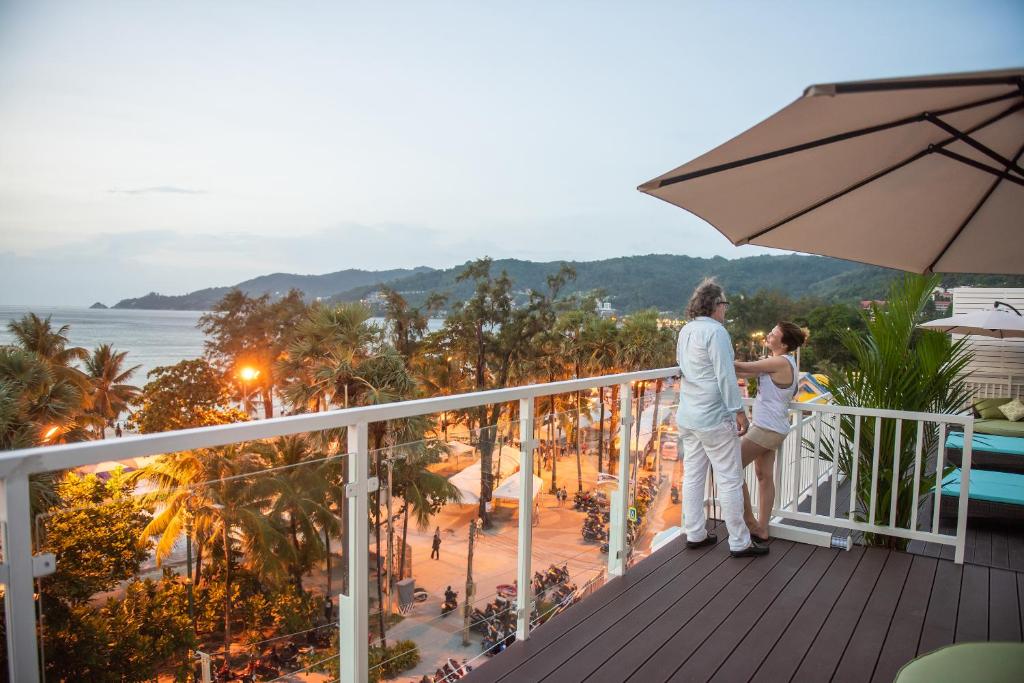 Una pareja de pie en un balcón con vistas al océano en Modern Living Hotel, en Patong Beach