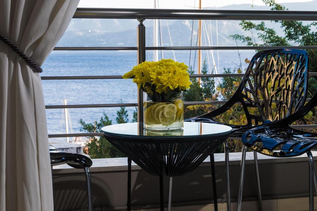 a glass vase with yellow flowers on a table in front of a window at Holy Paraskevi Apartment in Agios Nikolaos