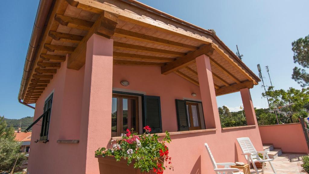 a house with a balcony with a wooden roof at Appartamenti La Casina in Porto Azzurro