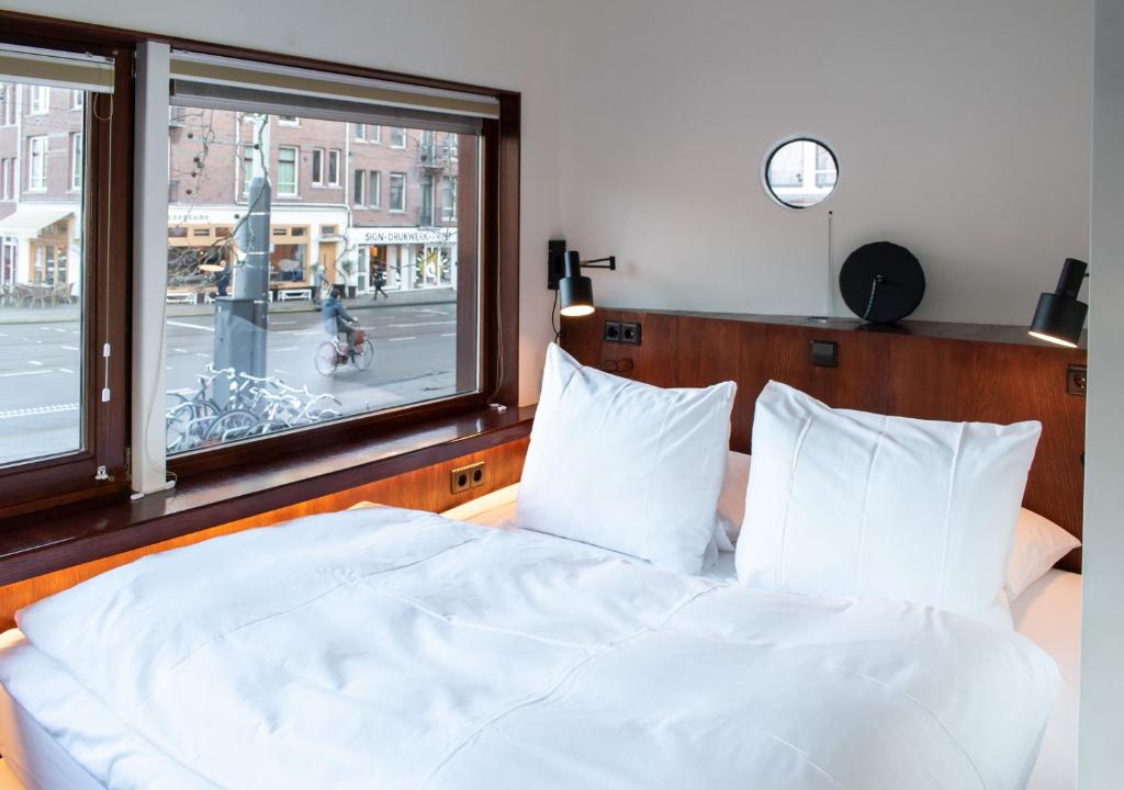 a bedroom with a white bed and a window at SWEETS - Zeilstraatbrug in Amsterdam