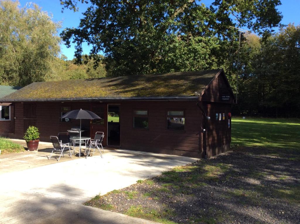 a shed with a table and chairs in front of it at The Firs in Ashford