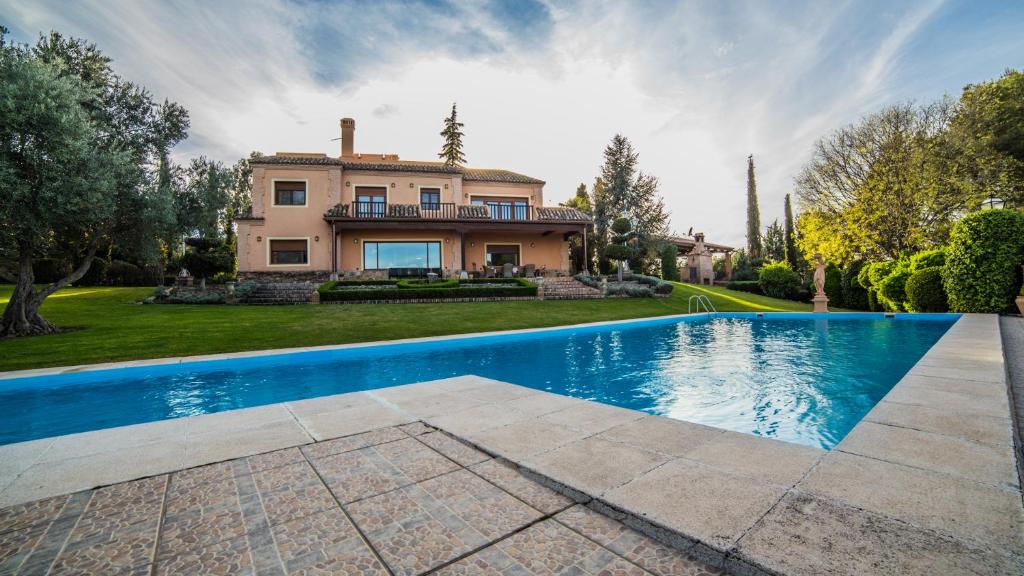 a home with a swimming pool in front of a house at Cigarral de la Encarnación in Toledo