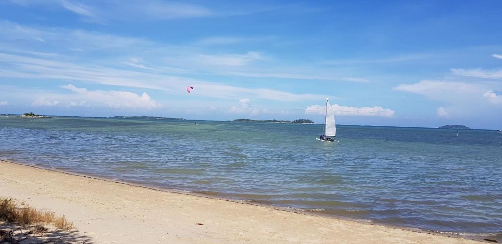 a sail boat in the water near a beach at Ten RooMs in Telukbakau