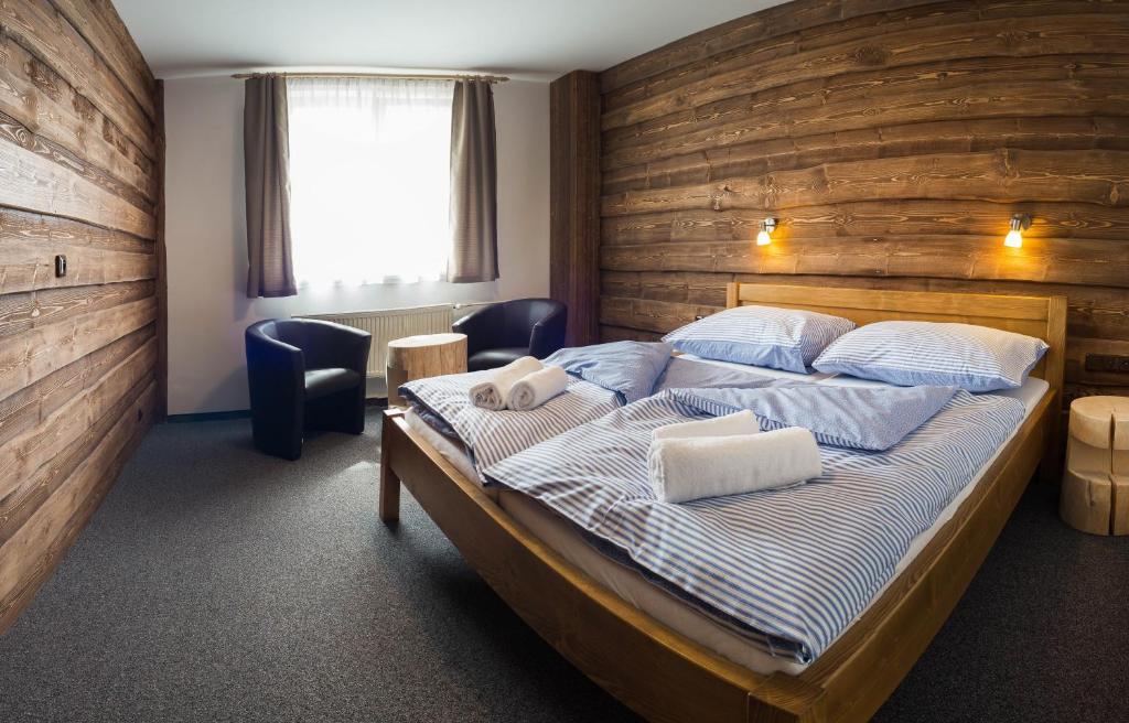 - une chambre avec un lit et un mur en bois dans l'établissement Hotel Kristian, à Kubova Huť