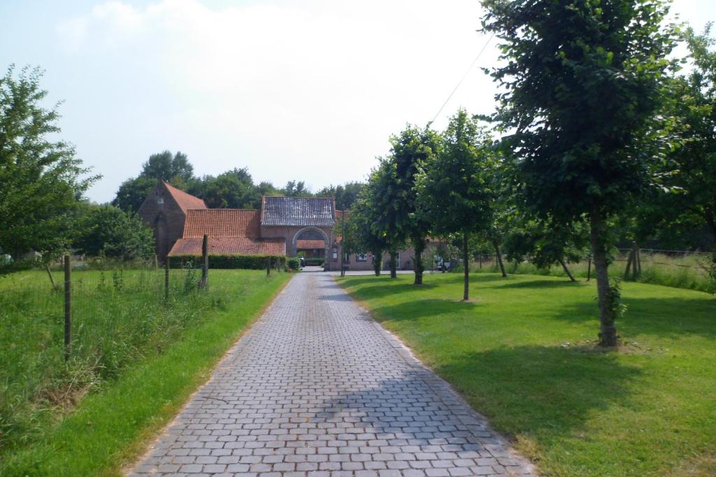 einen Backsteinweg in einem Park mit einem Gebäude und Bäumen in der Unterkunft Gîte de la Noyelle à Sainghin en Mélantois in Sainghin-en-Mélantois