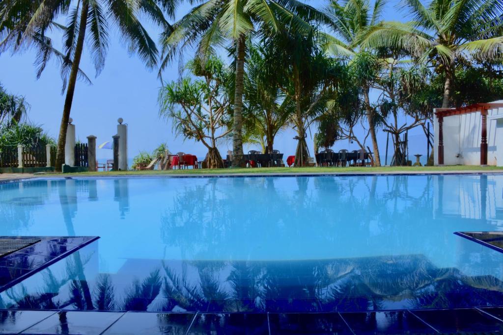 a large swimming pool with palm trees in the background at Southern Star Hotel in Bentota