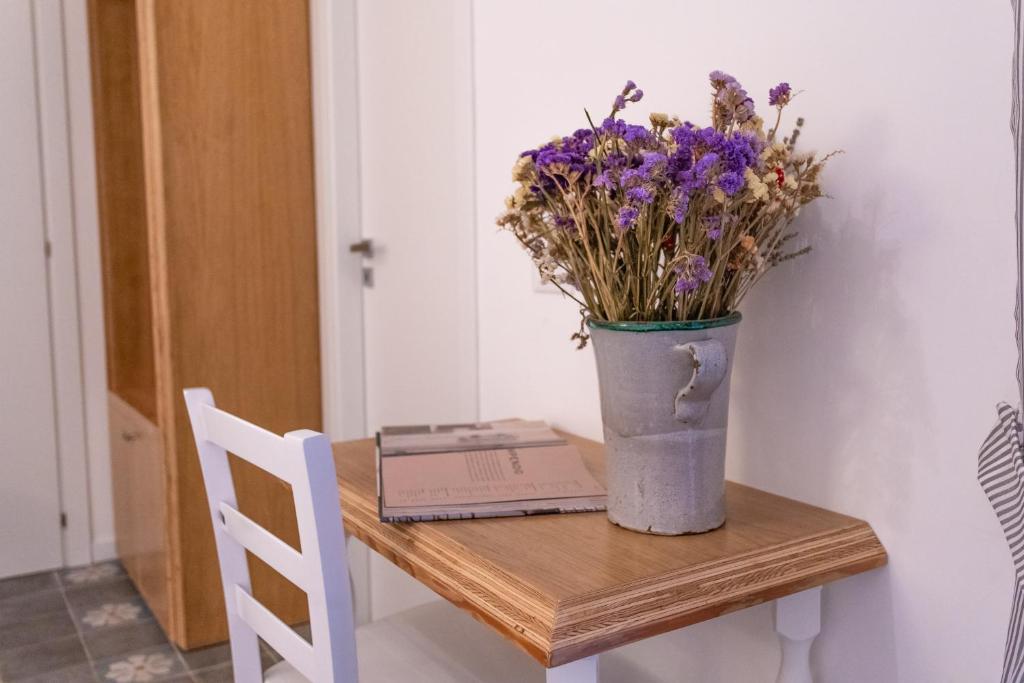 eine Vase mit Blumen auf einem Tisch mit einem Buch in der Unterkunft La Casa di Ro in Petralia Sottana