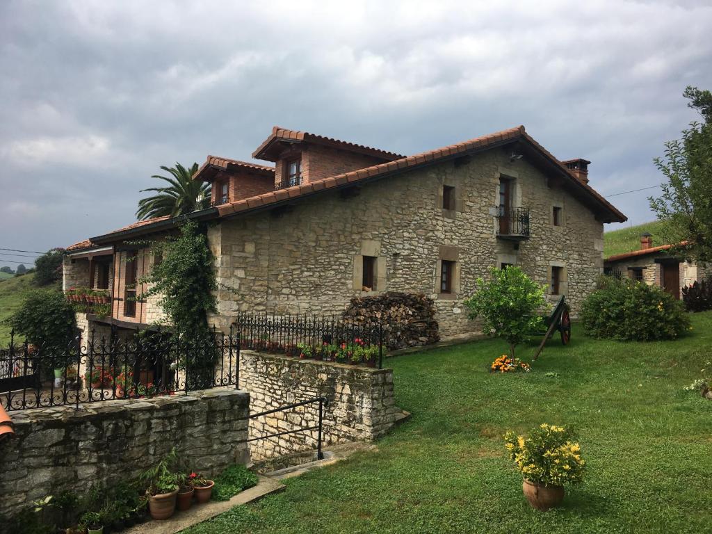 una casa de piedra con una valla y un patio en Casa Los Laureles, en Hinojedo