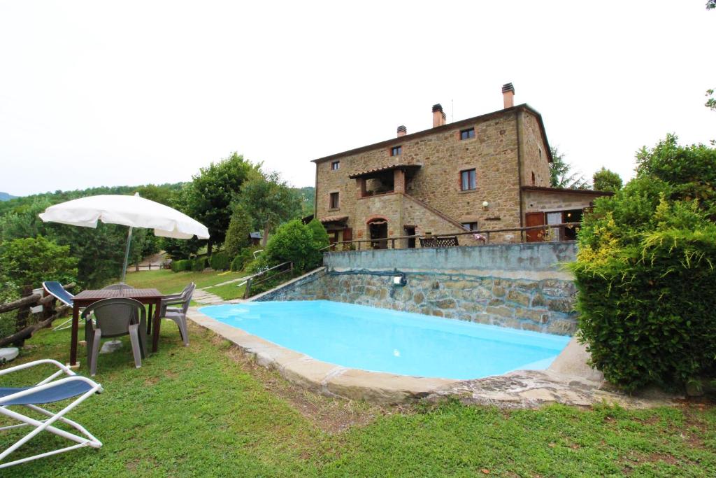 PoggioniにあるCasale Aiolaのスイミングプールと傘付きテーブルのある家