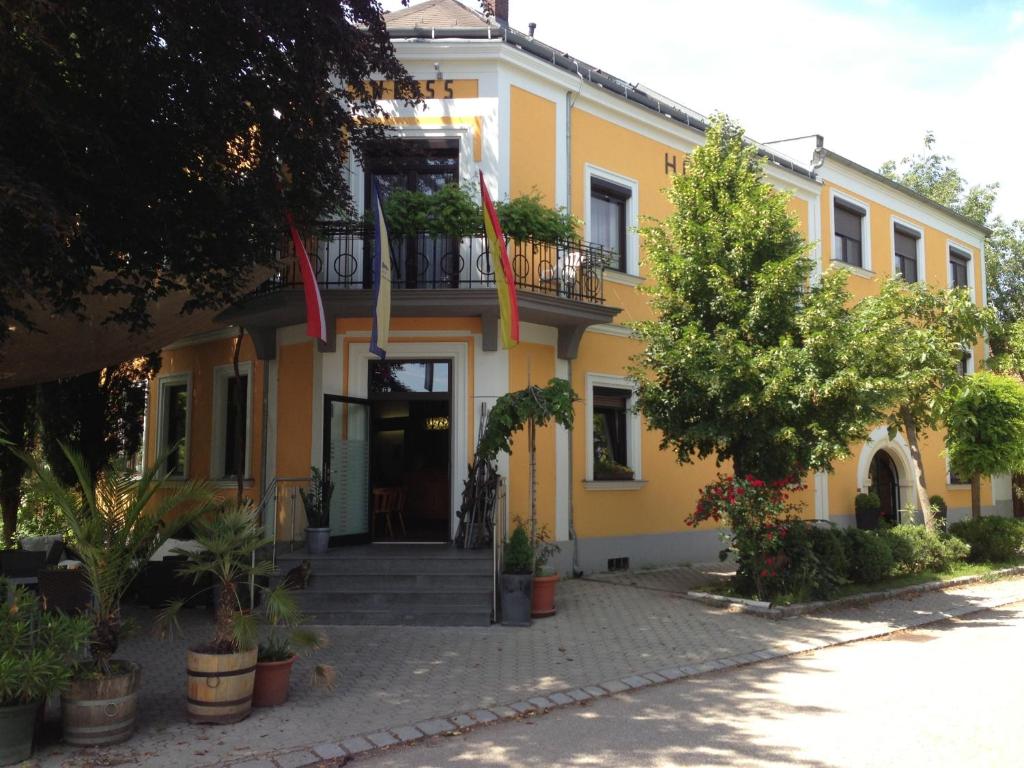 un bâtiment jaune avec des drapeaux à l'avant dans l'établissement Gasthof-Pension Weisz-Artner, à Frauenkirchen