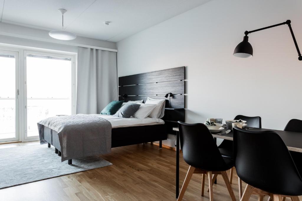 Schlafzimmer mit einem Bett, einem Schreibtisch und Stühlen in der Unterkunft Apartment Station in Oulu