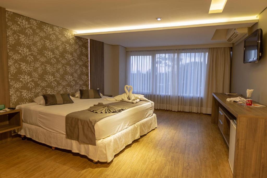 um quarto de hotel com uma cama grande e uma televisão em Continental Inn em Foz do Iguaçu