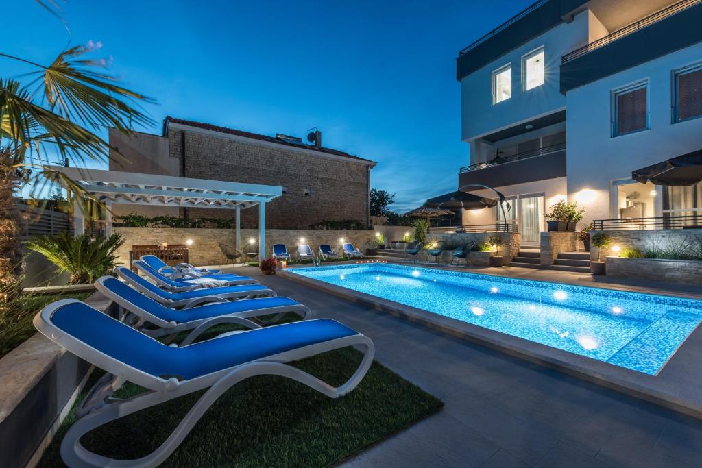 a swimming pool with lounge chairs next to a building at Penthouse apartment Polo in Bibinje