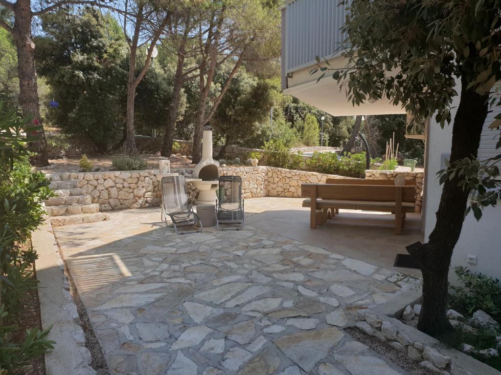 a stone patio with a bench and a table at Apartment Rina Deluxe in Šimuni