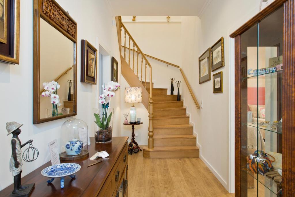 um corredor com uma escada com pisos em madeira e paredes brancas em Luxurious Pink House and Parking no Porto