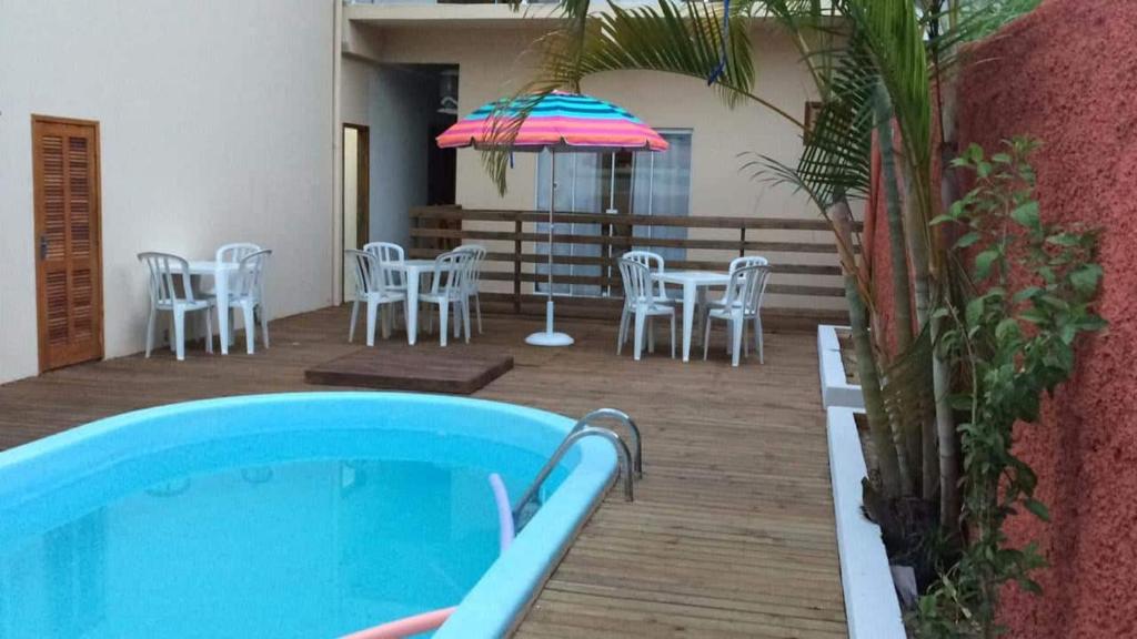 a patio with a pool and chairs and an umbrella at Pousada Vô Juca in Gravatal