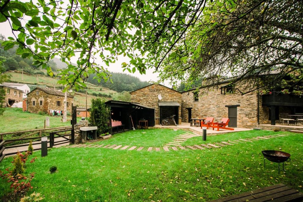 un patio trasero con una casa de piedra con patio en Casa Calma Rural, en Taramundi