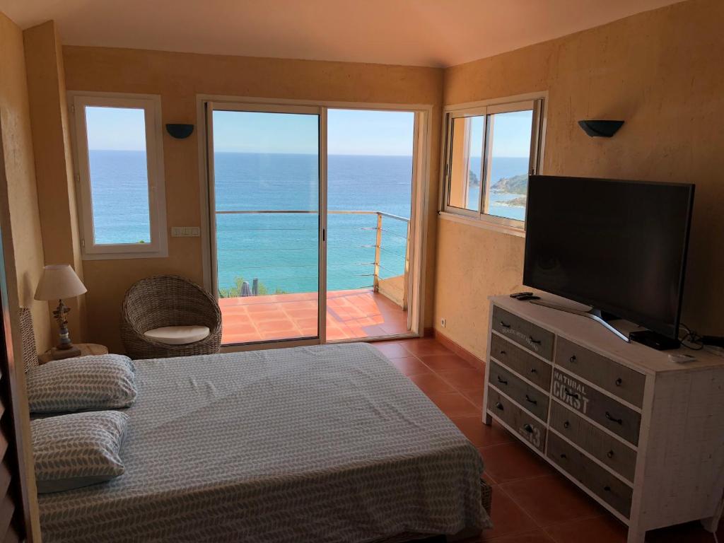 a bedroom with a television and a balcony with the ocean at Villa Rosa in Conca