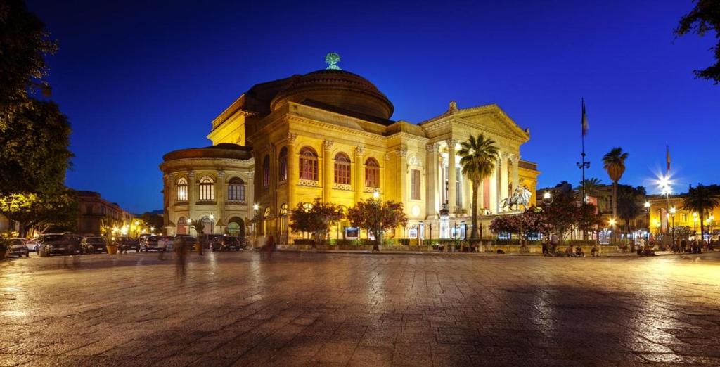 a large yellow building with a dome at night at Orologio del Massimo in Palermo